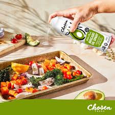 Person holding a package of 'Chosen' brand food over a tray of roasted vegetables.