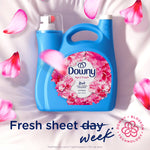 Blue Downy fabric softener bottle with floral design on a white background with pink petals.