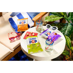 Table with Skinny Pop popcorn bags, sunglasses, and drinks in a casual setting.